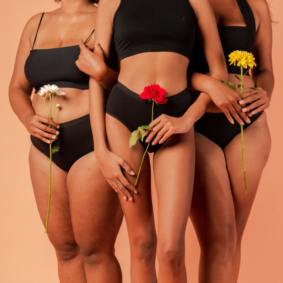 three models each wearing a black period underwear with flowers in their hands
